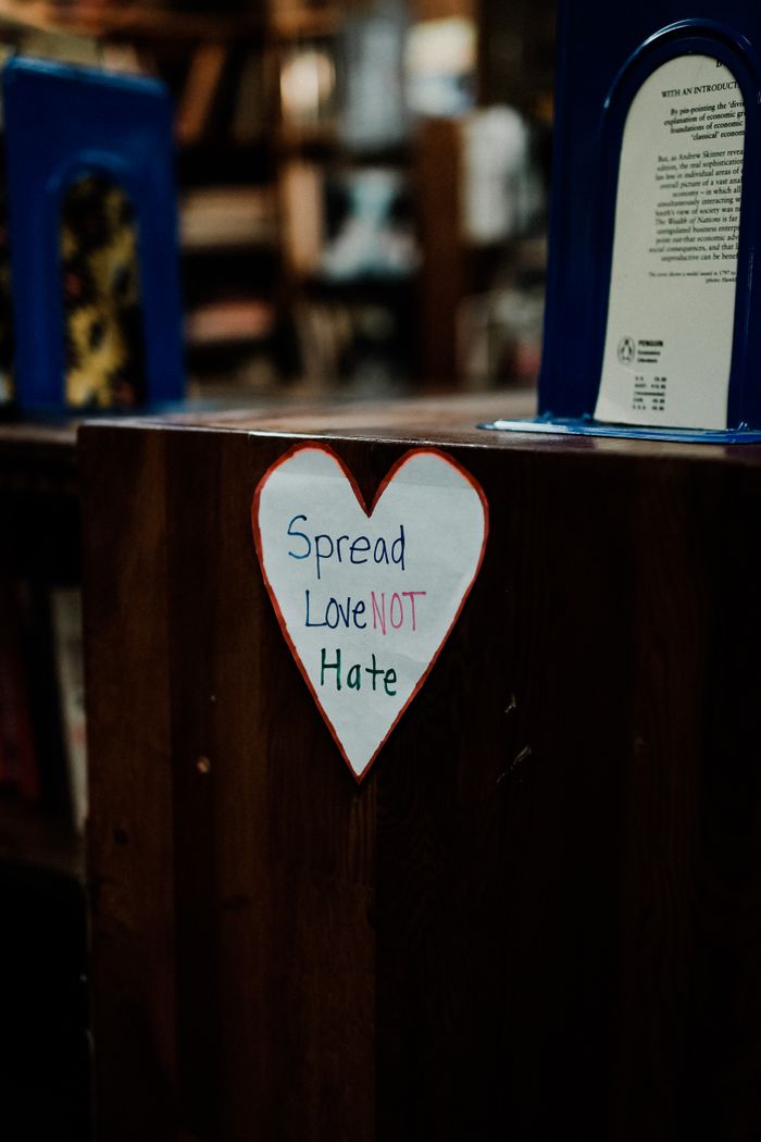 team-01 A heart-shaped sign with the message 'Spread Love Not Hate' in a library setting.
