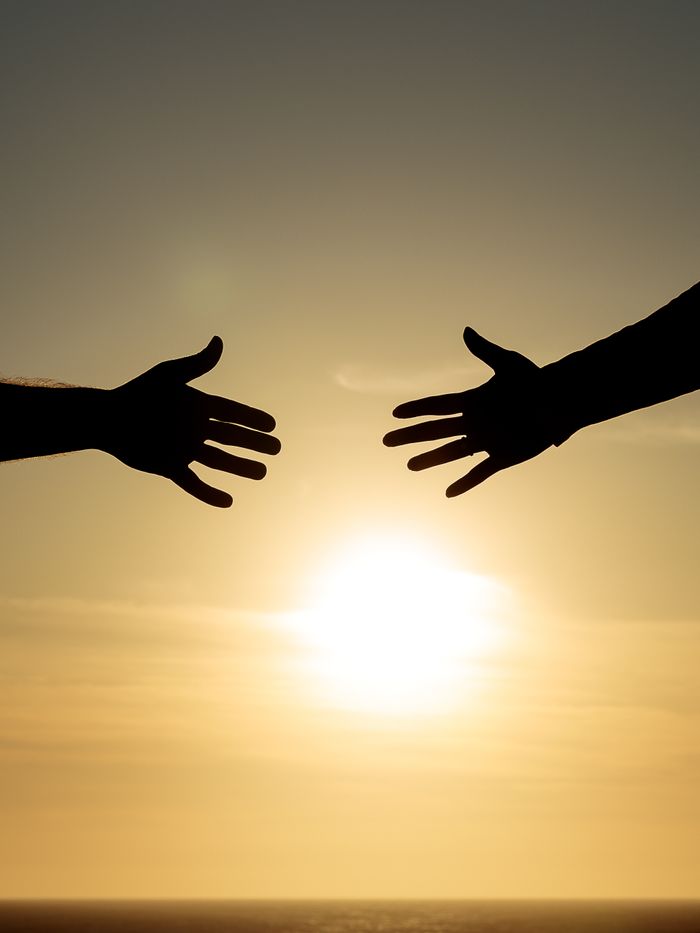 Crafting Captivating Headlines: Your awesome post title goes here Silhouetted hands reaching towards each other with the sun setting in the background.