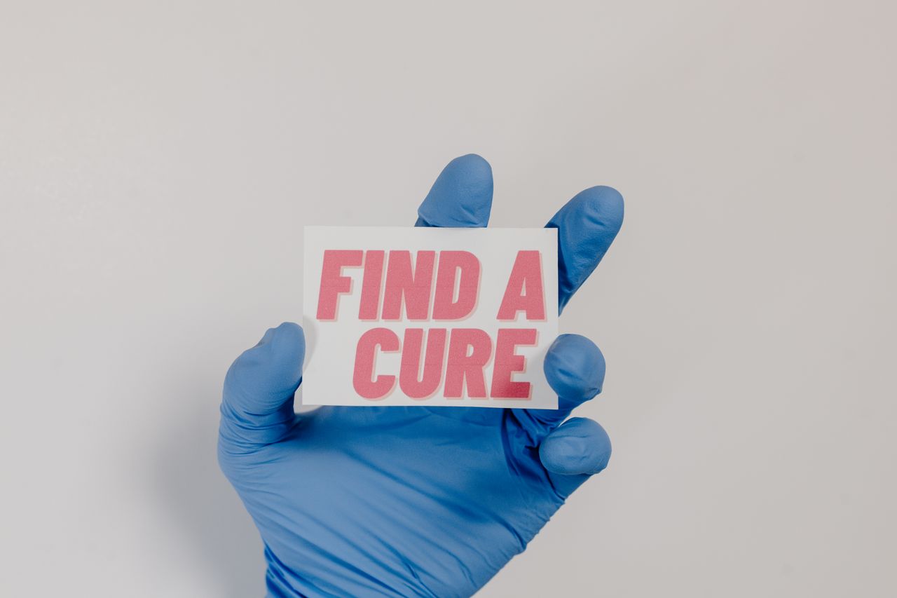 Mastering the First Impression: Your intriguing post title goes here A blue-gloved hand holds a card with 'Find a Cure' message, symbolizing cancer awareness.